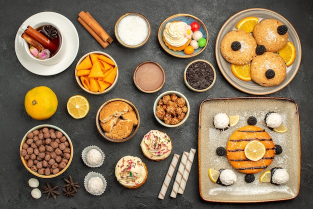 Vista de cima deliciosa torta com biscoitos e uma xícara de chá no bolo de superfície cinza, biscoito de chá, biscoito doce