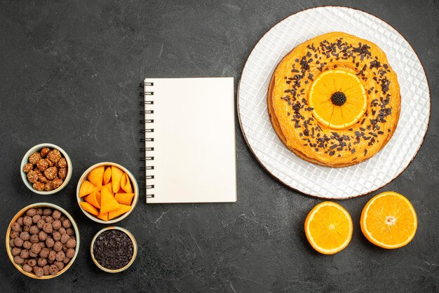 Vista de cima deliciosa torta com fatias de laranja em uma superfície cinza-escura doce de frutas biscoitos biscoitos de chá