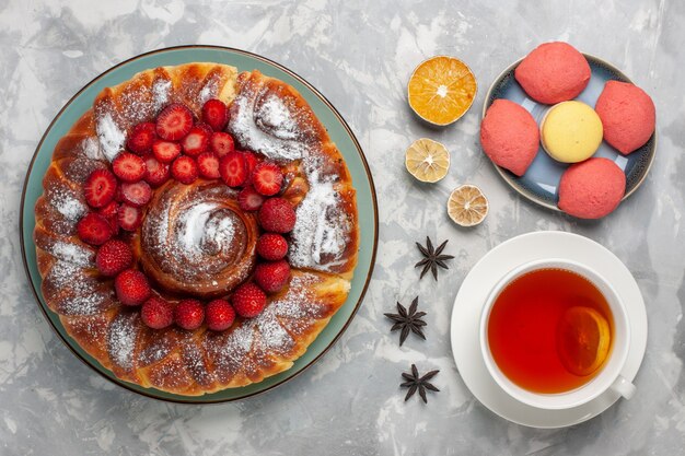 Vista de cima deliciosa torta de morango com bolinhos e xícara de chá na superfície branca torta de bolo biscoito doce açúcar chá assar