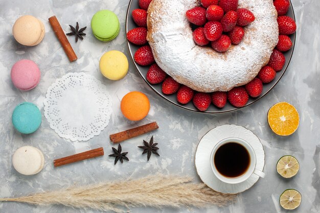 Vista de cima deliciosa torta de morango com chá e macarons em branco