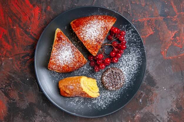 Vista de cima deliciosa torta fatiada com frutas vermelhas no bolo de torta doce de mesa escura