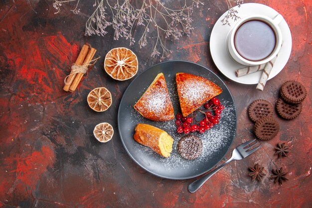 Vista de cima deliciosa torta fatiada com uma xícara de chá na mesa escura bolo torta doce chá