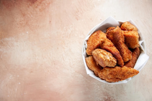 Vista de cima deliciosas asas de frango dentro do prato com guardanapos na superfície clara