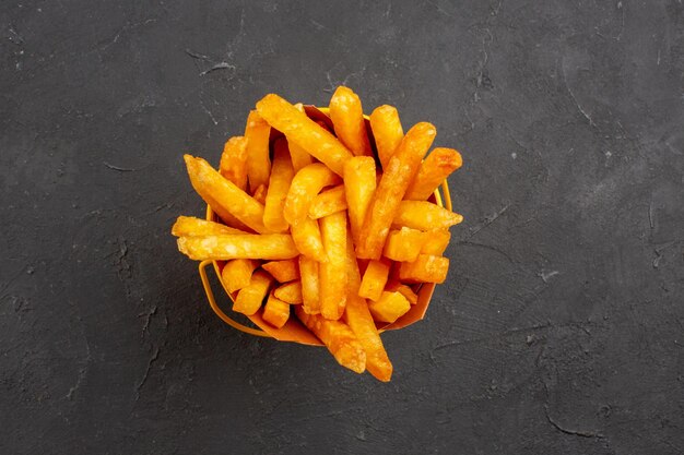 Vista de cima deliciosas batatas fritas em um fundo escuro refeição de hambúrguer prato de batata fast-food