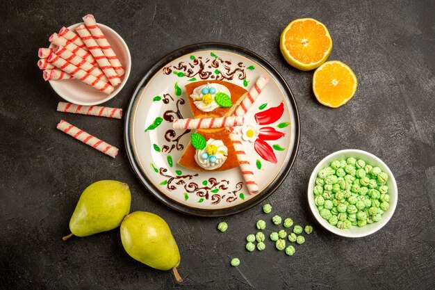 Vista de cima deliciosas fatias de torta com doces e frutas em cinza