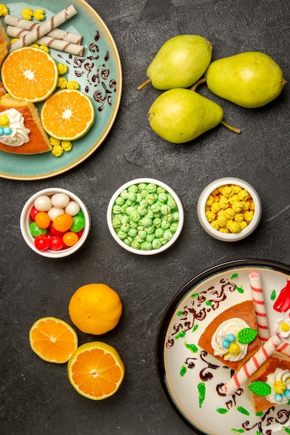 Vista de cima deliciosas fatias de torta com tangerinas fatiadas e peras em fundo cinza escuro frutas doces bolo massa torta chá