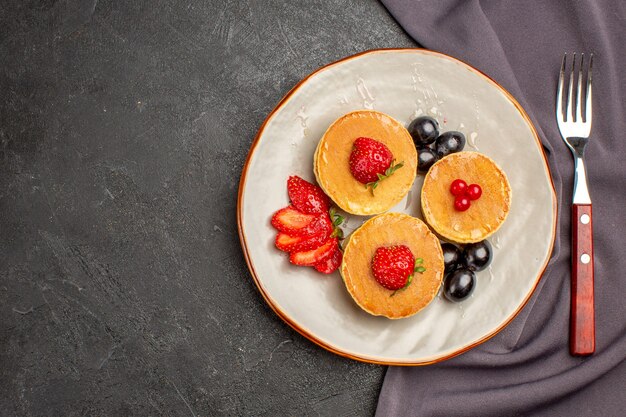 Vista de cima deliciosas panquecas com azeitonas e frutas no escuro