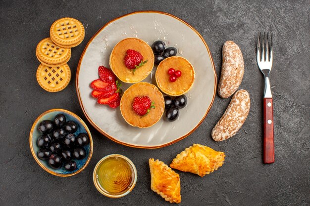 Vista de cima deliciosas panquecas com azeitonas e frutas no escuro