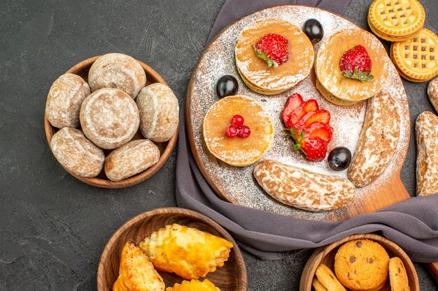 Vista de cima deliciosas panquecas com frutas e bolos doces no escuro