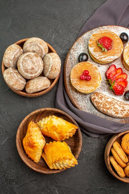 Vista de cima deliciosas panquecas com frutas e bolos doces no escuro