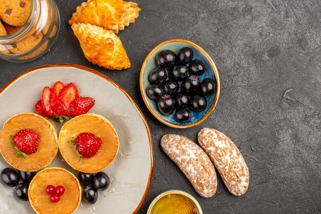 Vista de cima deliciosas panquecas com frutas e bolos no escuro