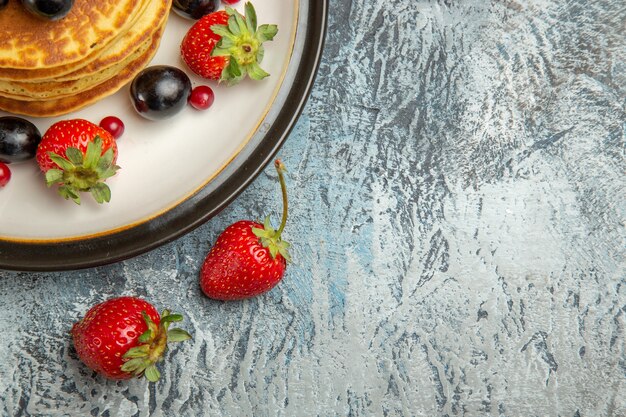 Vista de cima deliciosas panquecas com frutas em um bolo de frutas doce de superfície clara