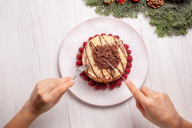 Vista de cima deliciosas panquecas com morangos em uma torta de mesa branca clara, biscoito de frutas e bolo doce de frutas vermelhas