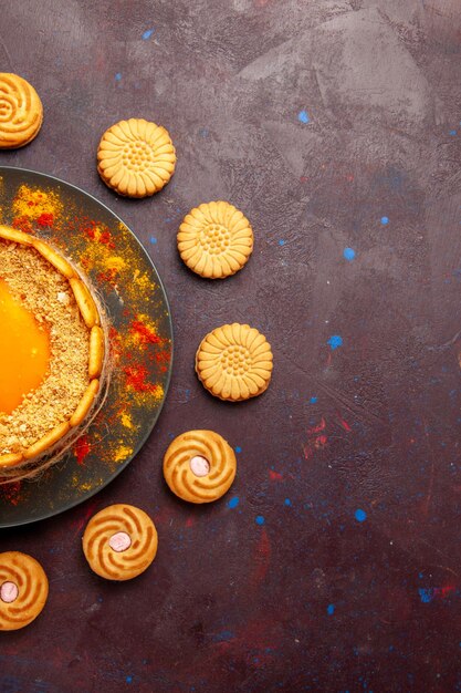 Vista de cima, delicioso bolo amarelo, sobremesa cremosa com biscoitos na mesa escura