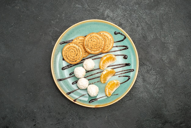 Vista de cima deliciosos biscoitos com bombons de coco e frutas na mesa cinza