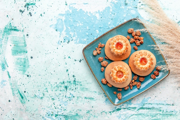 Vista de cima deliciosos bolos com biscoitos e nozes doces sobre fundo azul claro assar bolo de biscoito doce de nozes