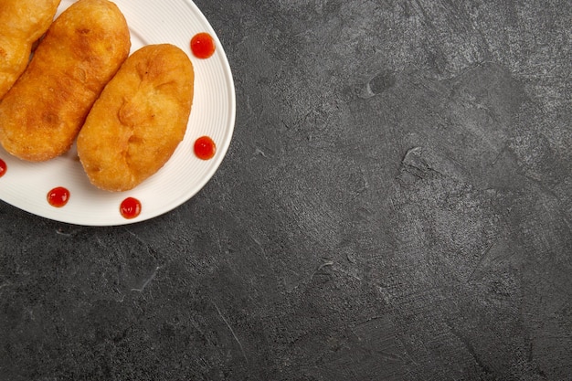 Foto grátis vista de cima, deliciosos bolos de batata dentro do prato em um fundo cinza escuro, torta de bolo de pão quente