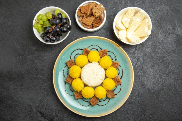 Vista de cima deliciosos doces amarelos com bolo de uvas e queijo na mesa escura açúcar frutas doces chá bolo doce