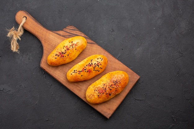 Foto grátis vista de cima deliciosos hambúrgueres recém-saídos do forno no fundo escuro torta massa folhada forno bolo carne assar