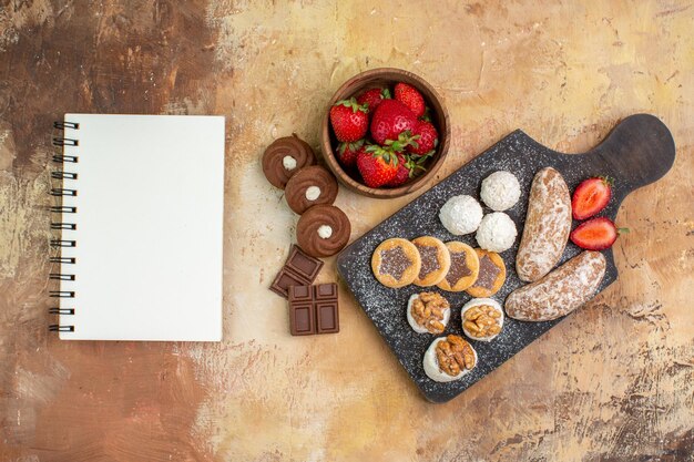 Vista de cima diferentes doces com biscoitos e frutas na mesa de luz