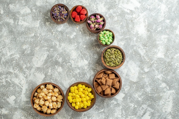 Vista de cima diferentes doces com nozes e flores na superfície branca doce chá açúcar bolo muitos