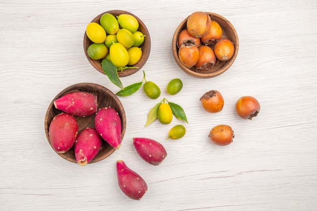 Vista de cima diferentes frutas frescas dentro de pratos em fundo branco frutas dieta tropical madura cor exótica