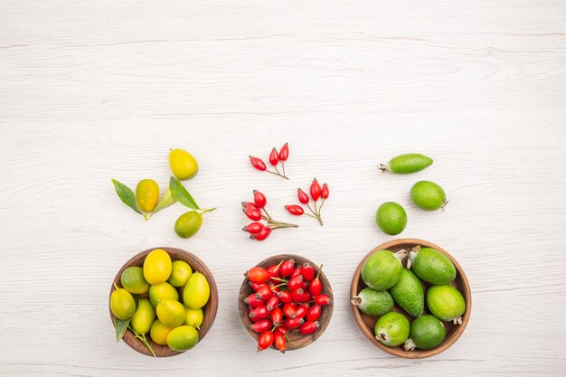 Vista de cima diferentes frutas frescas dentro de pratos na mesa branca dieta madura exótica cor vida saudável tropical