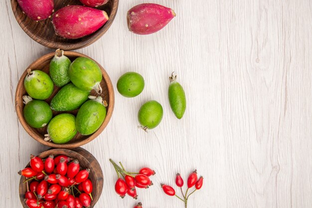 Vista de cima diferentes frutas frescas dentro de pratos no fundo branco dieta madura exótica cor vida saudável tropical
