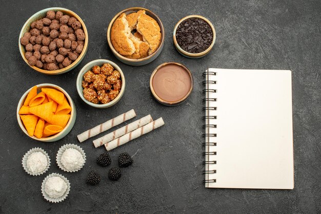 Vista de cima diferentes ingredientes cips, flocos e nozes na superfície cinza refeição lanche cor do café da manhã