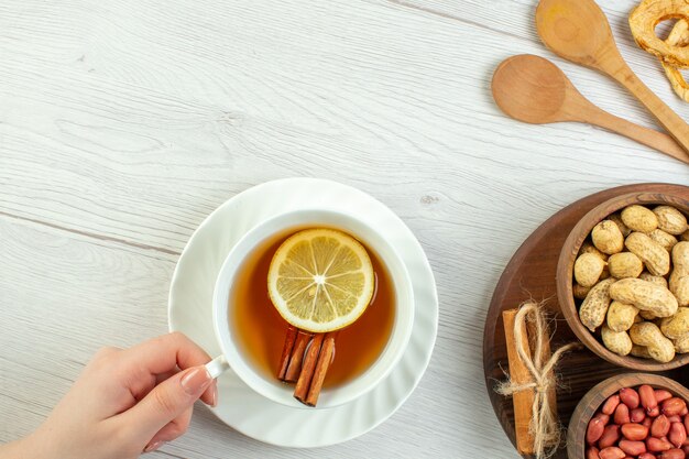 Vista de cima diferentes nozes, amendoim, avelãs e nozes com uma xícara de chá na mesa branca