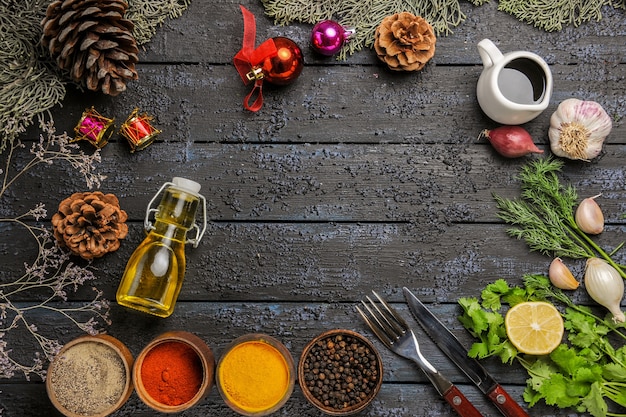 Vista de cima diferentes temperos com óleo e verduras na mesa escura