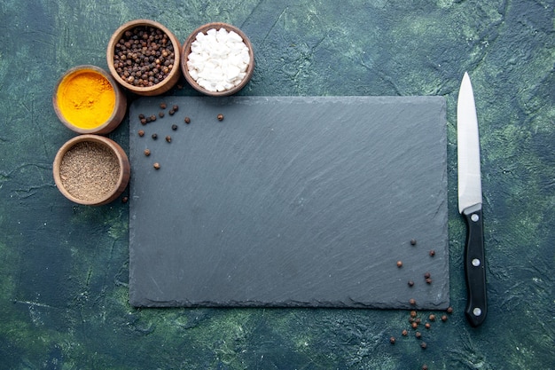 Vista de cima diferentes temperos na superfície azul escuro para alimentos sal pimenta cor da foto