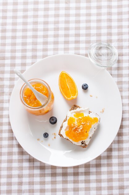 Vista de cima do café da manhã com pão e laranja marmelada
