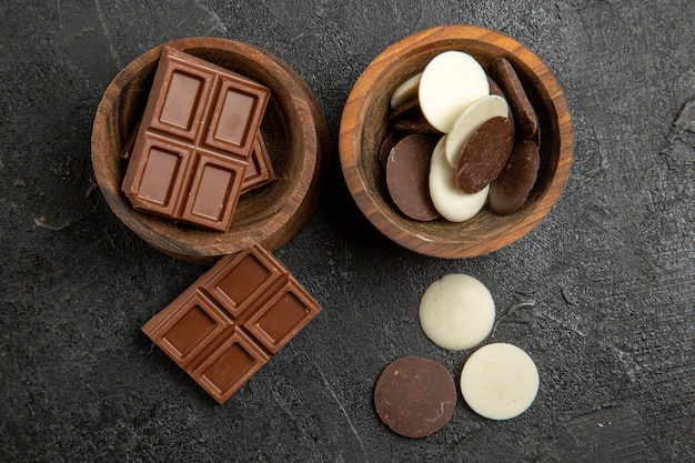 Vista de cima, em close-up, chocolate com chocolate em tigelas marrons na mesa escura