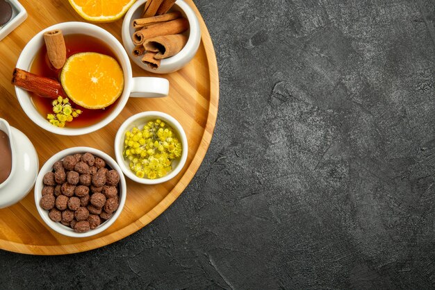 Vista de cima em close-up com chocolate limão tigelas de chocolate com creme de nozes uma xícara de chá com palitos de cinnabon e limão no lado esquerdo da mesa