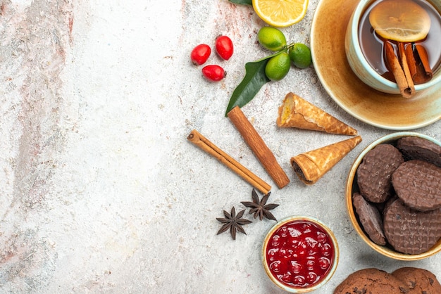 Vista de cima em close-up cookies, uma xícara de chá com limão, canela, frutas cítricas, compota, anis estrelado