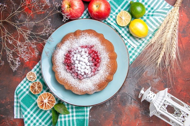 Vista de cima em close-up de um bolo um bolo com frutas cítricas açúcar de confeiteiro em pó na toalha de mesa quadriculada