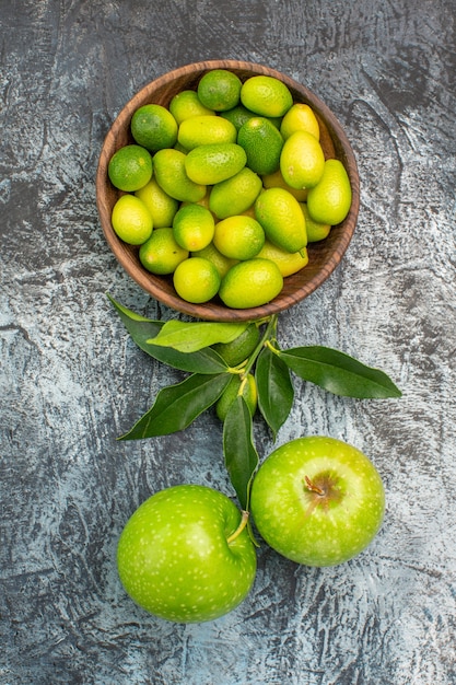 Vista de cima em close-up frutas, frutas cítricas apetitosas na tigela e duas maçãs