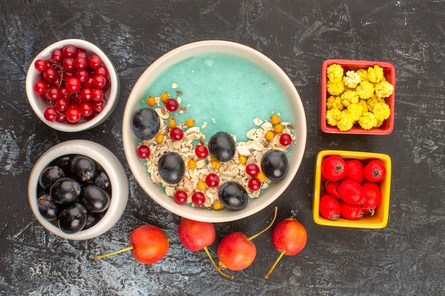 Foto grátis vista de cima em close-up prato de frutas vermelhas de aveia e frutas tigelas de doces de uvas vermelhas