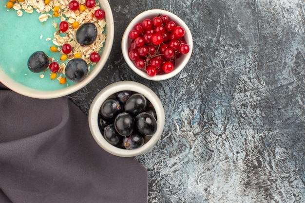 Vista de cima em close-up taças de frutas vermelhas de groselha e aveia de uvas na toalha de mesa