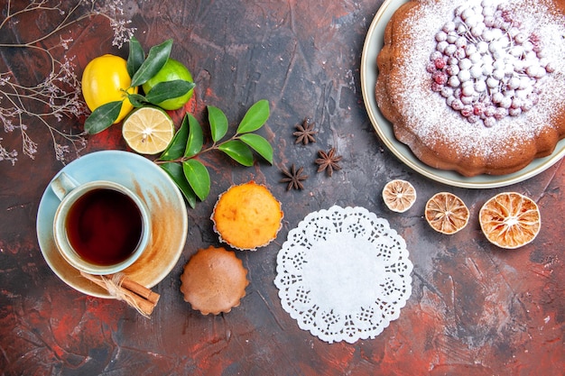 Vista de cima em close-up uma xícara de cupcakes de chá uma xícara de chá canela renda doily frutas cítricas um bolo