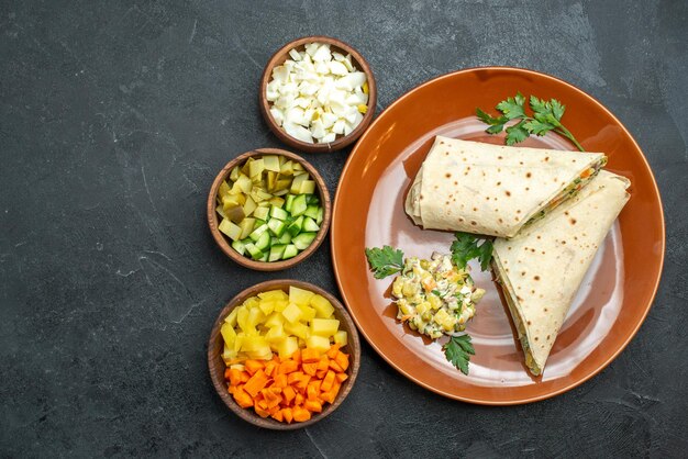 Vista de cima em fatias de carne saborosa shaurma e sanduíche de salada na superfície cinza sanduíche de hambúrguer com salada de pão carne sírio