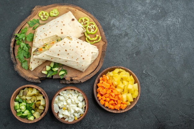 Vista de cima em fatias saborosas de sanduíche de salada shaurma em uma refeição de superfície cinza com salada de hambúrguer pita