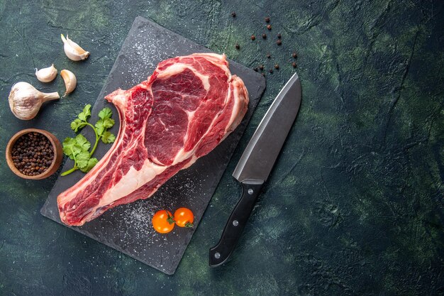 Vista de cima em uma grande fatia de carne crua com pimenta na superfície escura