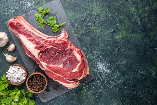 Foto grátis vista de cima em uma grande fatia de carne crua com pimenta na superfície escura