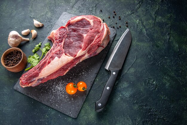 Vista de cima em uma grande fatia de carne crua com pimenta na superfície escura