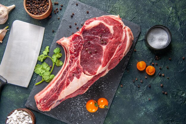 Vista de cima em uma grande fatia de carne crua com pimenta na superfície escura