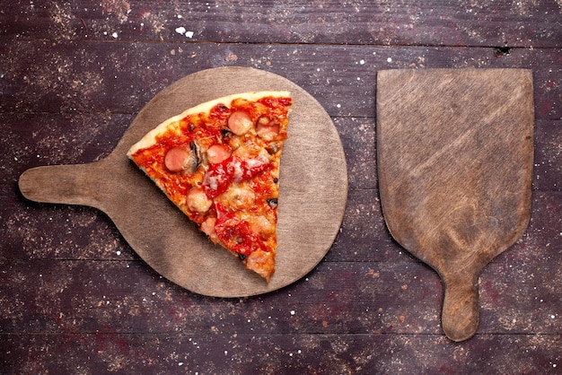 Foto grátis vista de cima, fatia de pizza gostosa com salsichas, queijo, tomates e azeitonas no fundo de madeira marrom.