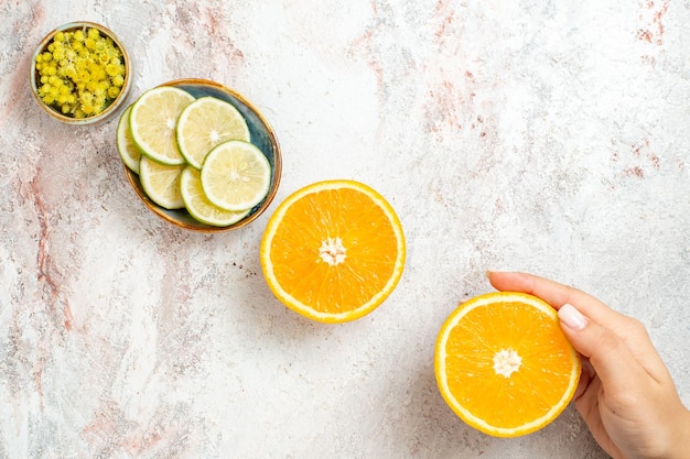 Vista de cima fatias de limão fresco com laranja na mesa branca