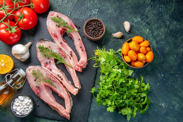 vista de cima fatias de peixe fresco com tomates vermelhos e verduras em fundo escuro